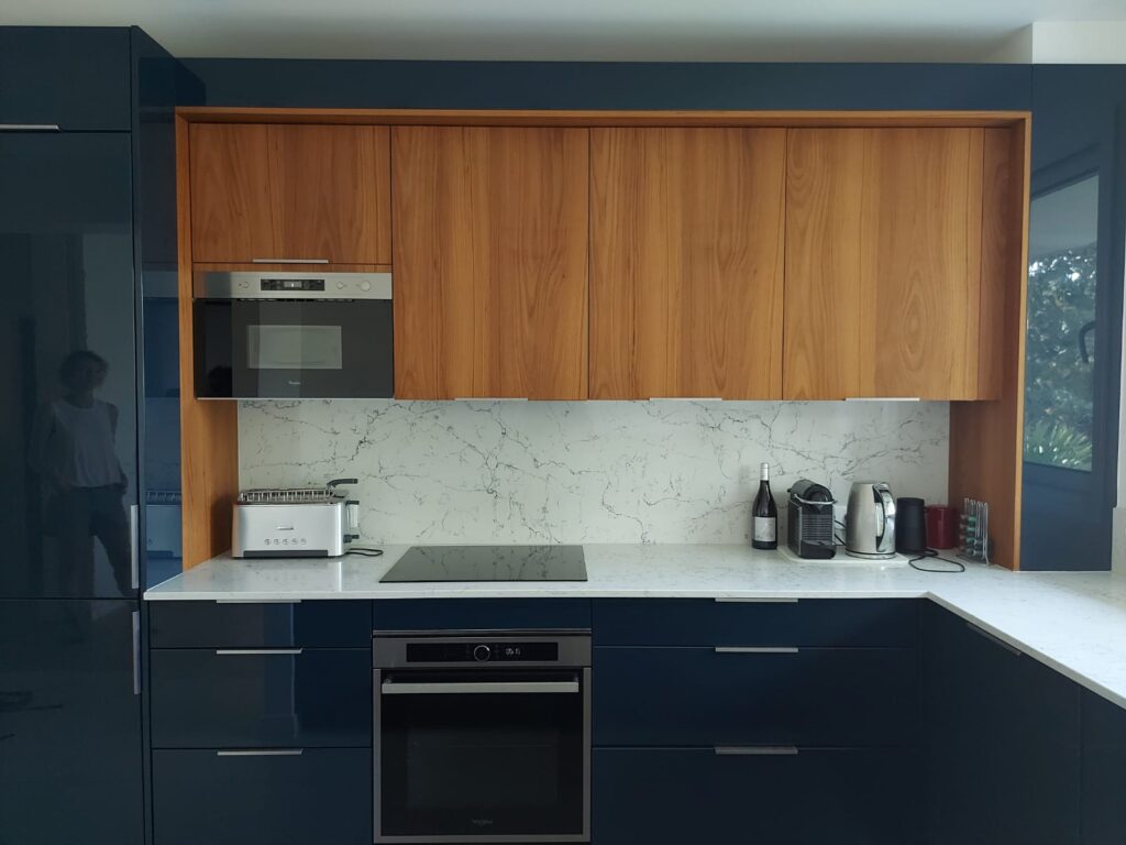 Cuisine sur-mesure bleu et bois ambré. avec arche sur les meubles hauts, micro-ondes intégré, et plan de travail quartz matanuska veiné