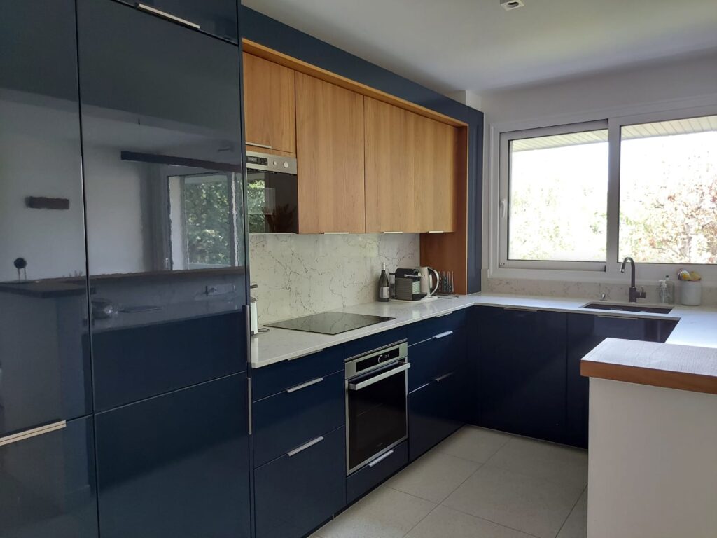 Cuisine sur-mesure bleu et bois ambré. avec arche sur les meubles hauts, micro-ondes intégré, et plan de travail quartz matanuska veiné