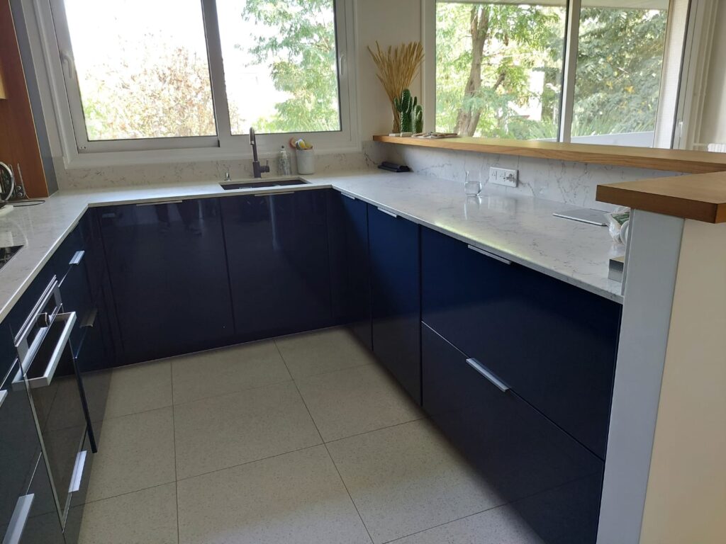 Cuisine sur-mesure bleu et bois ambré. avec arche sur les meubles hauts, micro-ondes intégré, et plan de travail quartz matanuska veiné